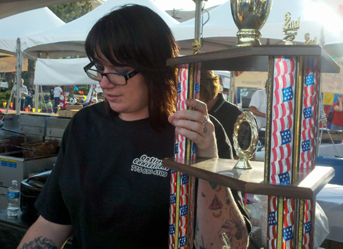 Keila Tidwell of Onstreet Concessions serves a customer wings while standing next to their trophy from last year's Reno event.