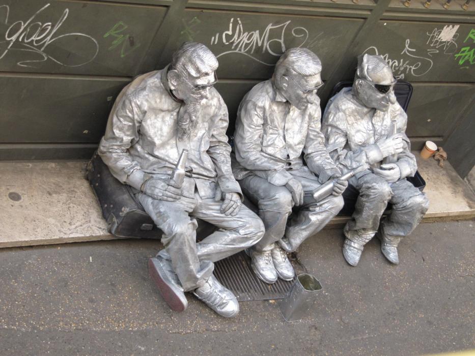 Three street performers pretending to be motionless statues while seated near the Coliseum in Rome. Photo by Don Quilici