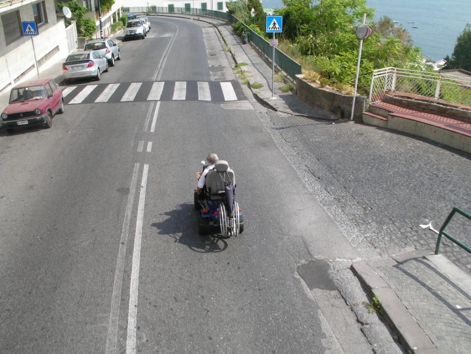 A man in a motorized wheelchair on a busy street in Taromini.  Photo by Don Quilici