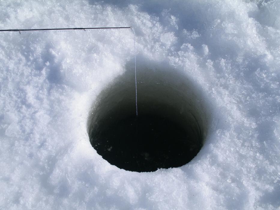 Ice fishing requires constant attention to keeping the hole open.  Photo by Don Quilici