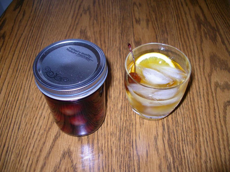 A jar of brandied cherries next to a cocktail. Photo by Elaine Quilici