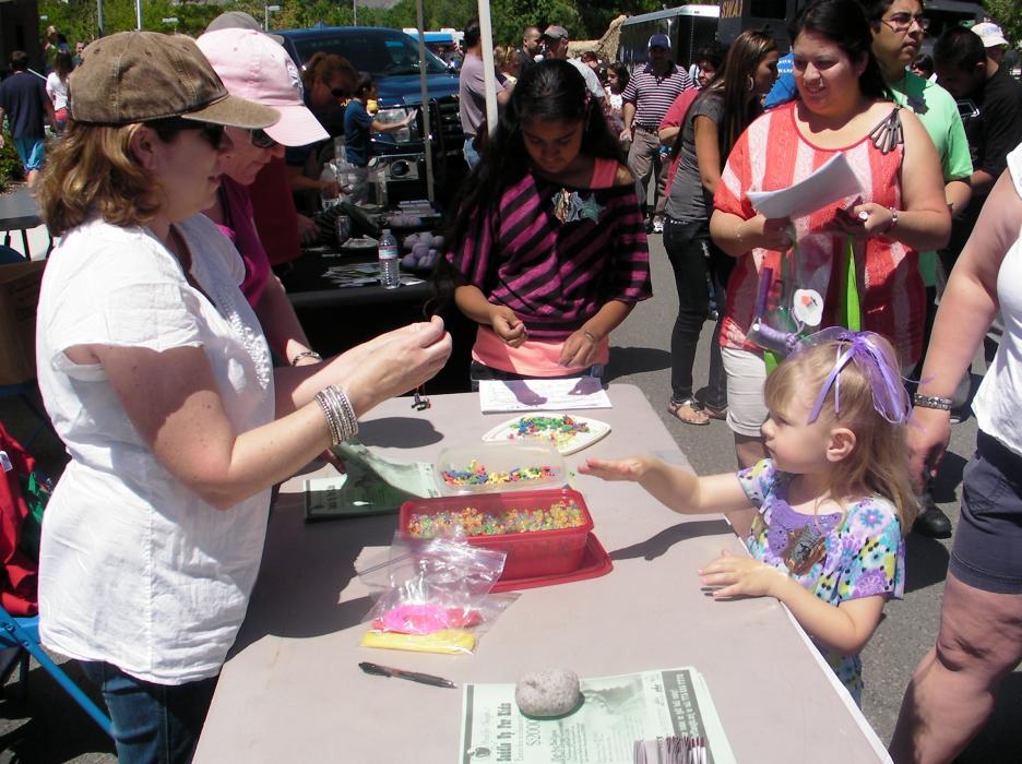 Volunteer Stephanie Gardner gives Izzabelle Marriott a bead bracelet.