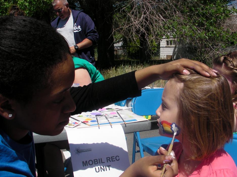 Helina Ashagrie paints the face of Ellie Loos, 6 at the Boys and Girls Club booth.