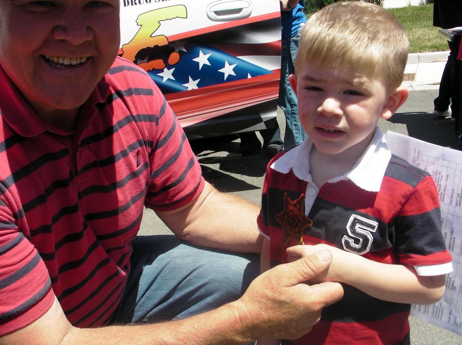 Reg Larson and grandson Jasper Elliott show off a sheriff's office badge.