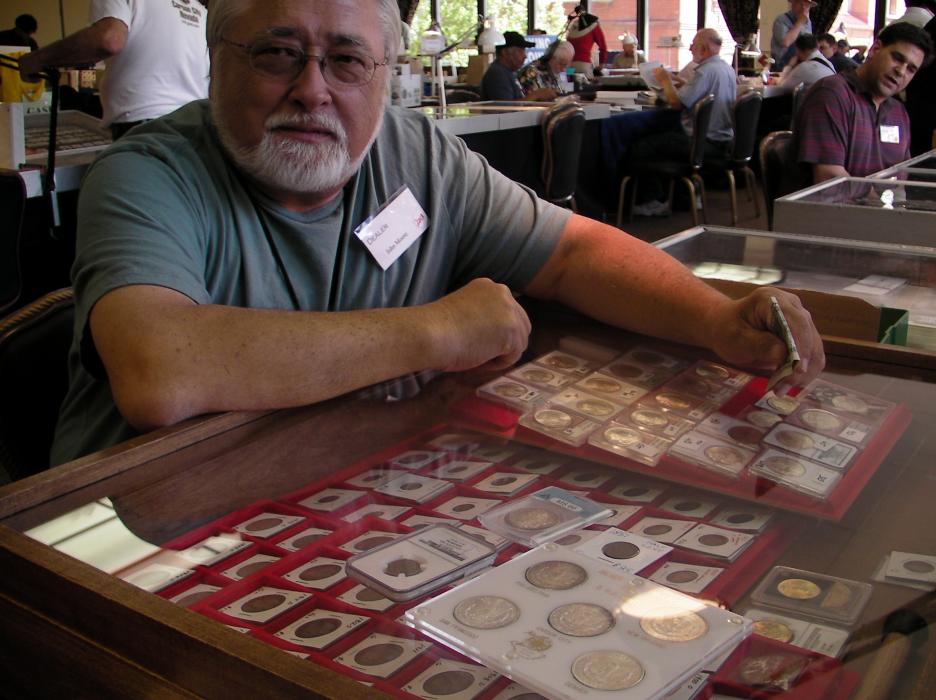Coin collector John Moore in front of a display.