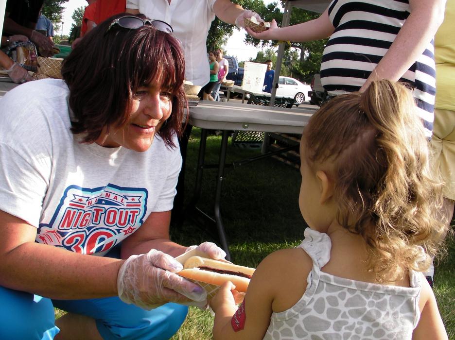 Lani McKinley of the Carson City Sheriff's Office shares a hotdog with Harmony Lawton, 3, of Carson City.