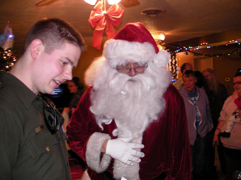 Reserve Sgt. Matt Helleckson and Santa watch gifts being unwrapped.