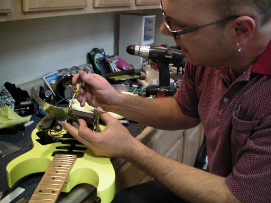 Play Your Own Music store owner Vince Gates repairs an electric guitar.