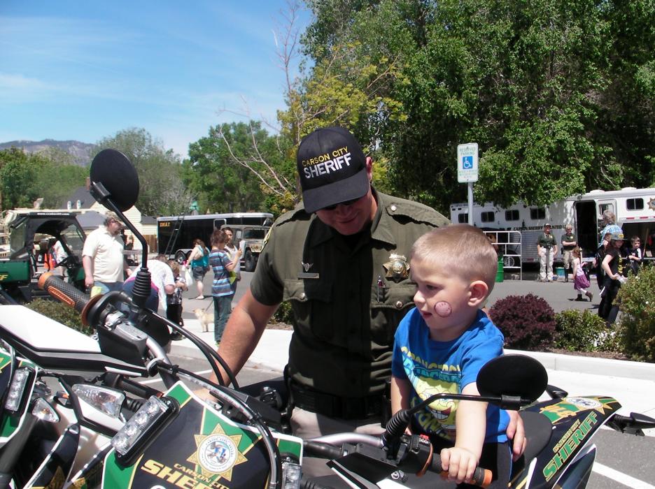 Carson City sheriff's motor patrol deputy Joey Trotter helps Nehemiah Feagan, 3, on a motorcycle Saturday..