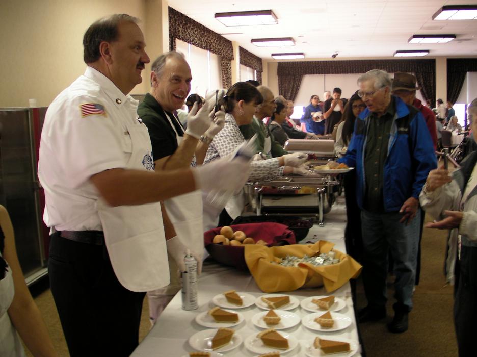 Carson City Fire Chief Stacey Giomi and Sheriff Ken Furlong dish up rolls and pie.