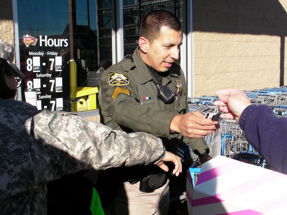 Carson City Sheriff' Sgt. Daniel Gonzales helps pass out $100 gift cards to children and volunteers.