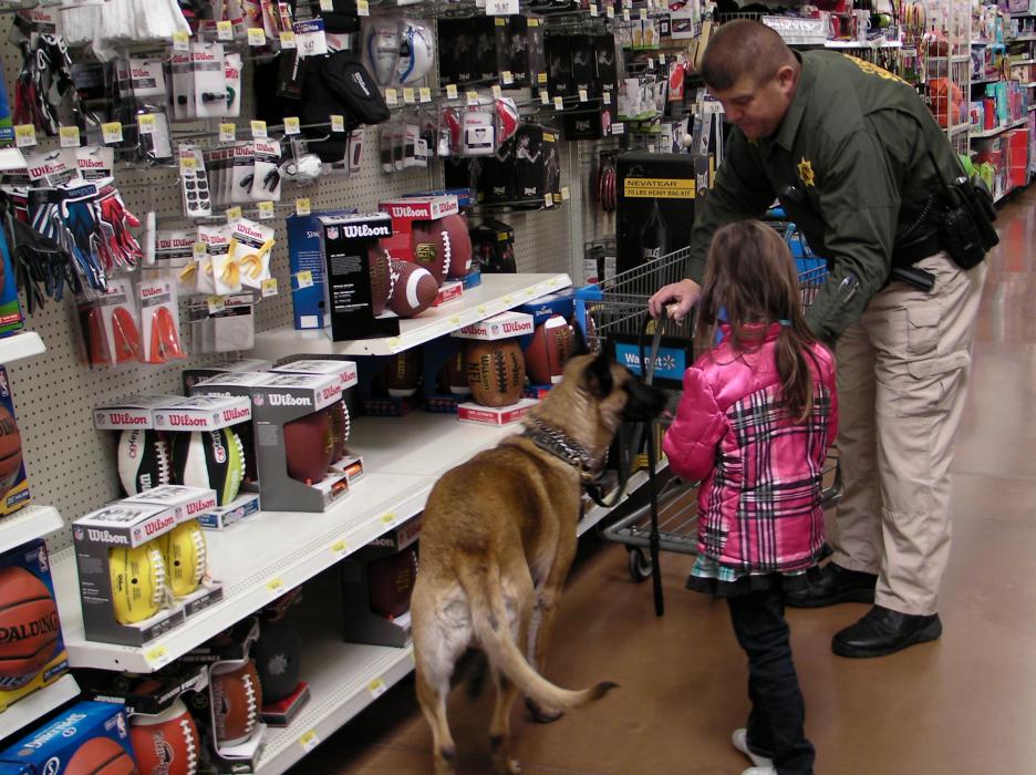 Carson City sheriff's deputy Jeff Pullen with K9 Rex helps this girl pick out a toy.