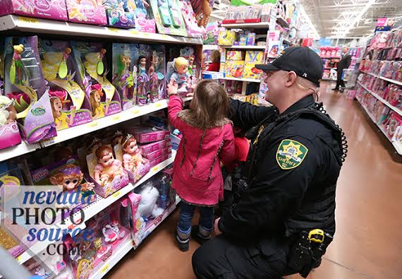 Carson City Sheriff's Tri-Net Deputy Dan Jones helps this little lady shop for dolls. Photo by Cathleen Allison of Nevada Photo Source.