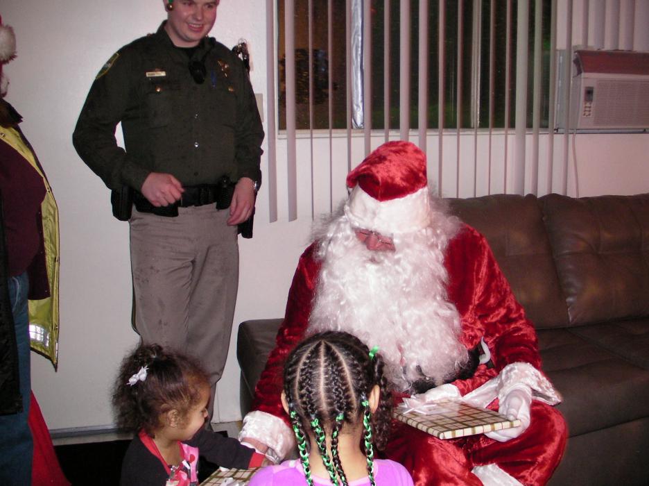 Santa delivers toys and more to the Harrison home as Deputy Reserve Officer Matt Helleckson watches.