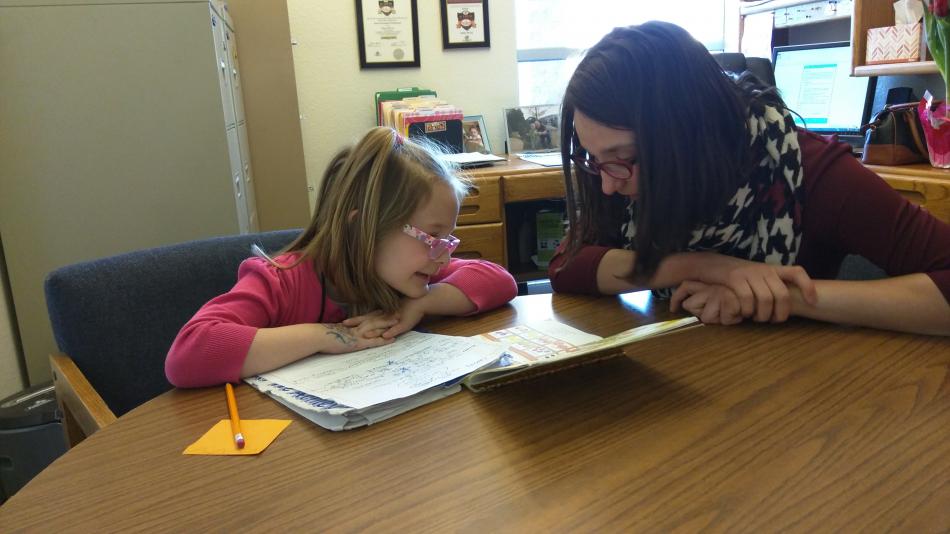 Autumn helps 6-year-old Cassidy Shoeppler sound out words in her workbook.