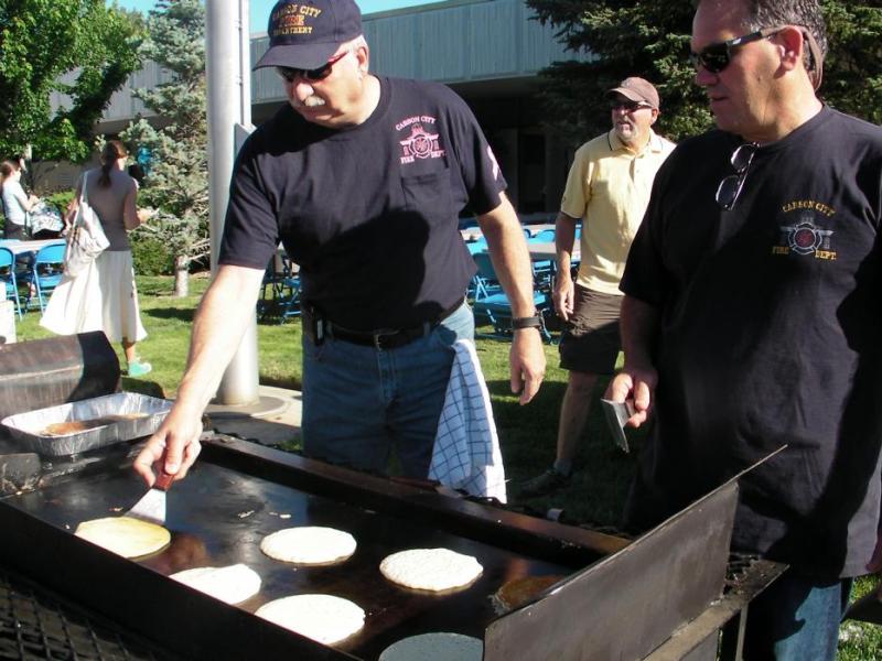 Tom Tarulli, Assistant Fire Chief, and Carson City Fire Chief Bob Schreihans flip hotcakes at the library.