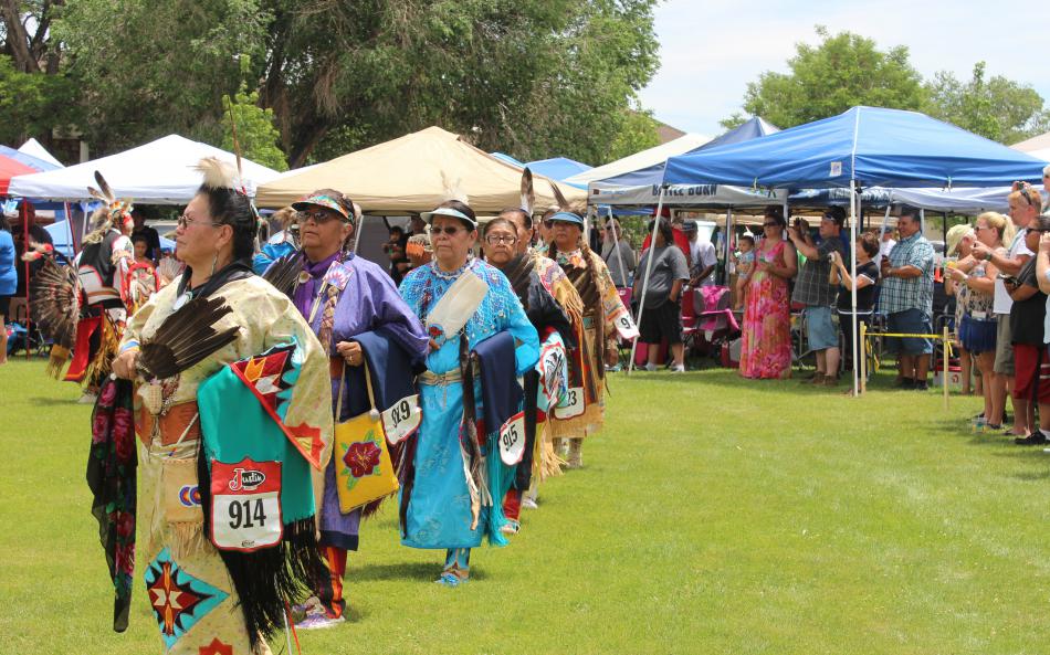 Women equipped with woven handbags and feathers waltz through the arena