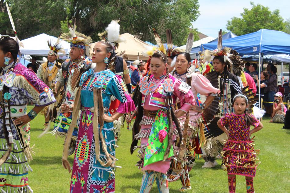 Women wearing jingle dresses dance to the Native American national anthem