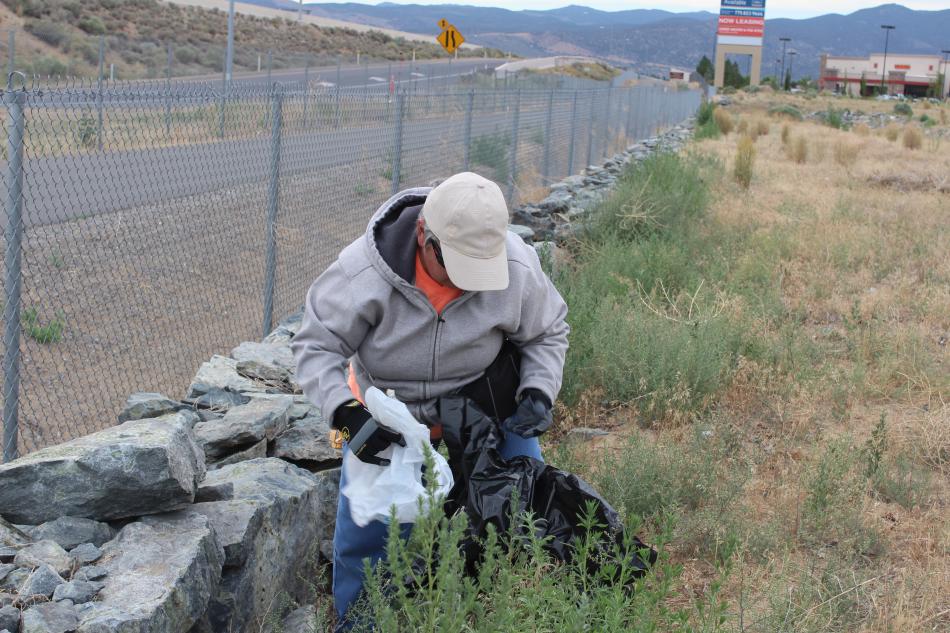 A volunteer picks up a Walmart bag, blown to the area from the Walmart nearby.