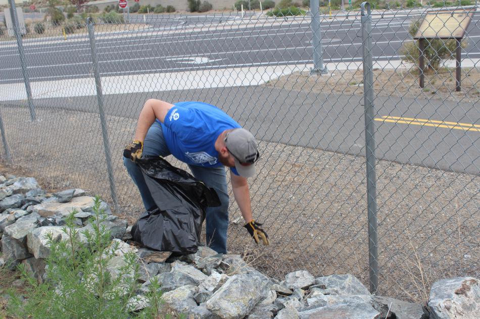 Randy Gaa, a Muscle Power volunteer and organizer of the trash mob picks up trash that has blown against the fence.