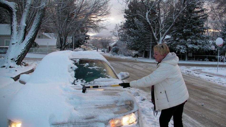 Mari Otto cleans off her car at the intersection of Division and William Street on Monday morning in Carson City.
