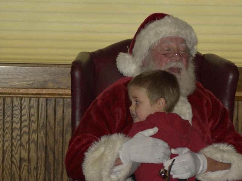 Santa hugs a visitor as everyone around enjoyed treats