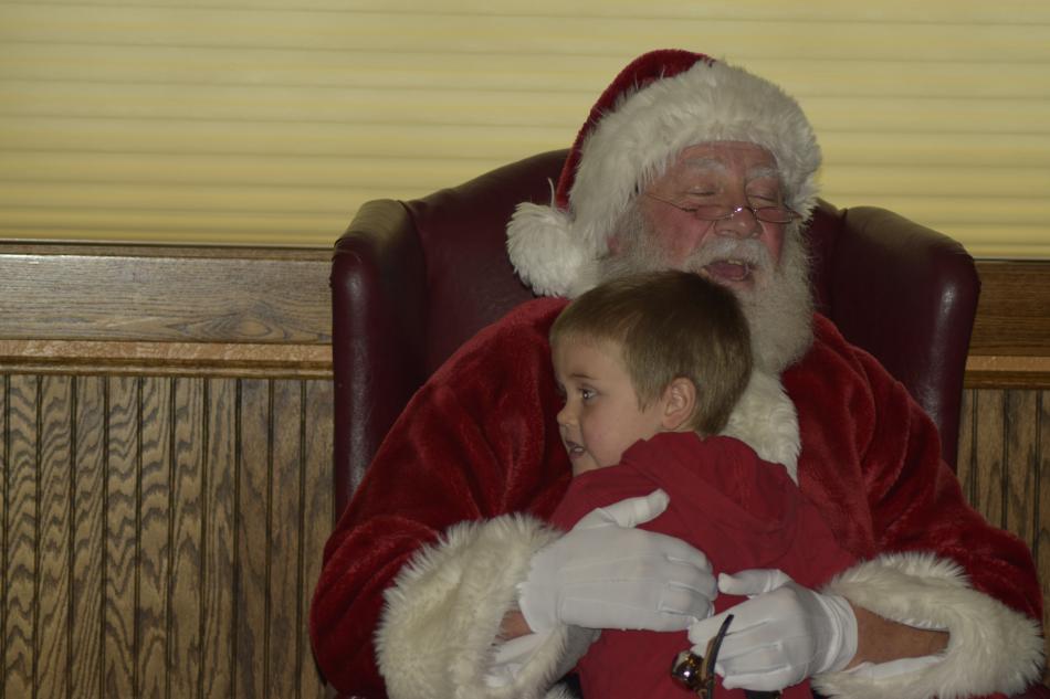 Santa hugs a visitor as everyone around enjoyed treats