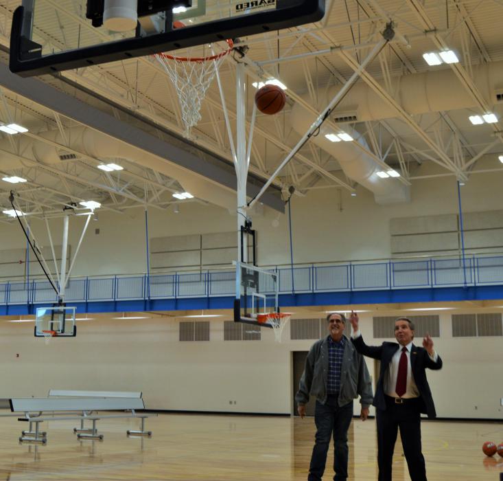 Mayor Bob Crowell and Bill Miles of Miles Construction shoot the first baskets on the court of the new MAC.