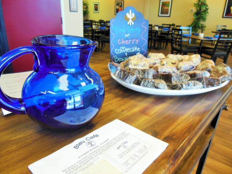 The front counter at Bleu Cafe, dressed with a hand-blown glass pitcher and a plate of fresh coffee cakes made from scratch.