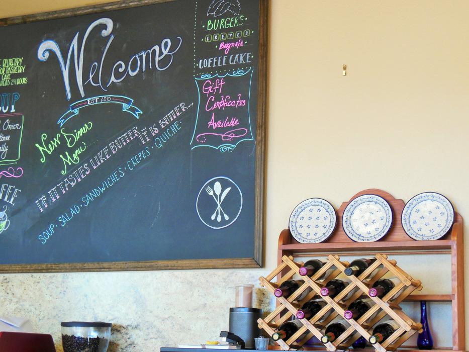 The welcome board behind the front counter at Bleu Cafe, featuring the restaurant's slogan.