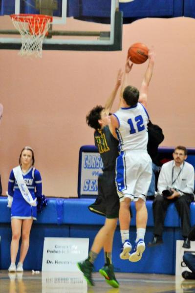 Asa Carter (12) reaches for a lay up against a Manogue defender Tuesday night at Carson High School.