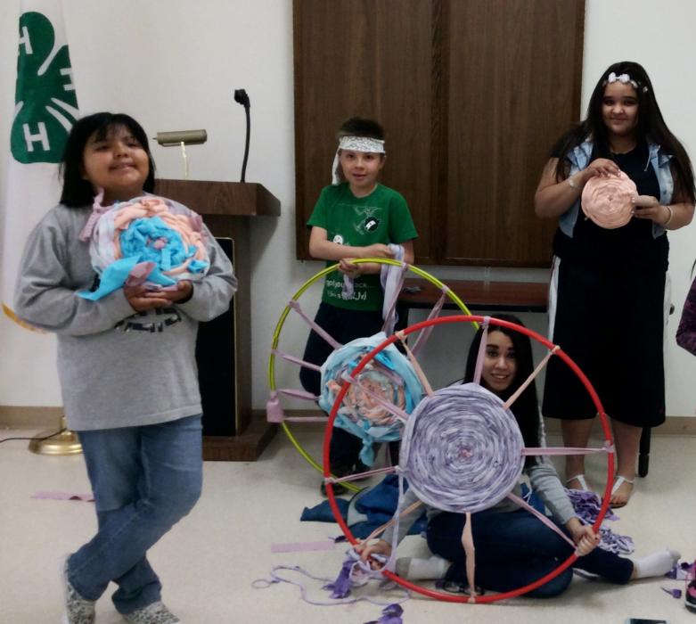 Charlie Lee, left, Taeja Rossback, seated, and Isabella Cardona, right, show off rugs they made on Hula Hoop looms.