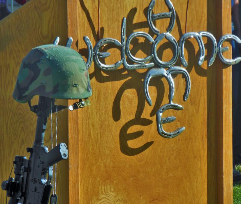 Welcome Home sign with fallen soldier marker at the speaker's podium.