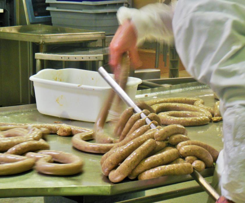 Freshly cased links are placed on racks in preparation for curing.