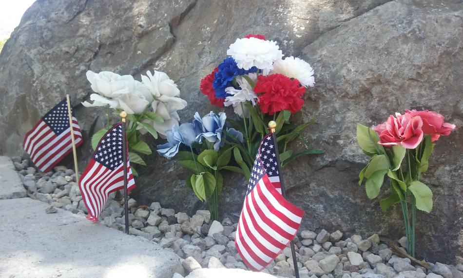 Flowers and flags at the base of the Carson City monument at the Korean War Veterans Memorial.