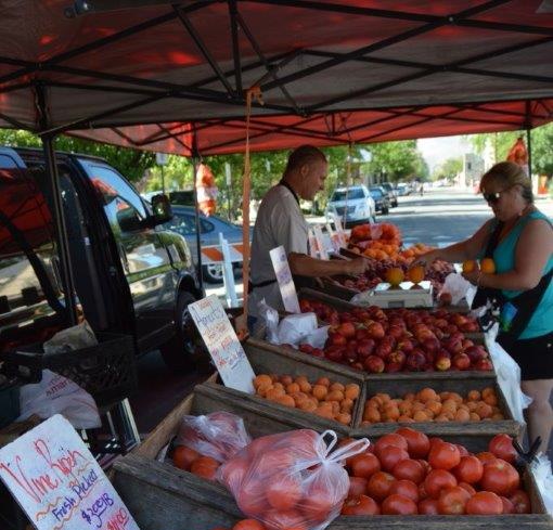 Photo by Lisa Fisher. A produce vendor and a buyer Wednesday along Curry St.