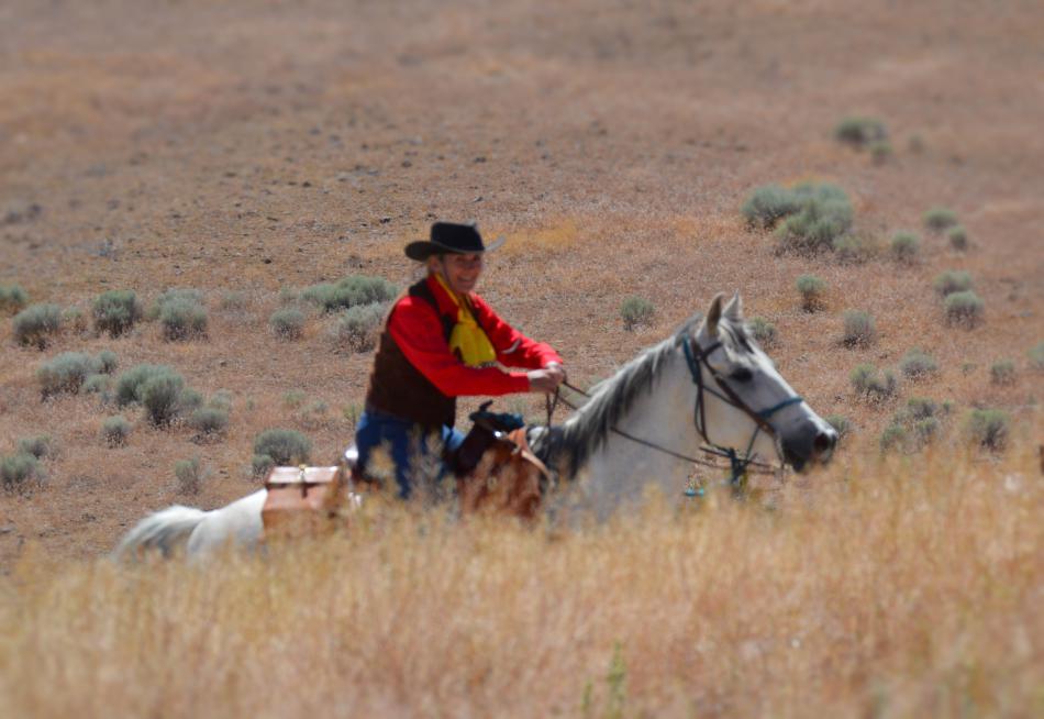 Photo by Lisa Fisher. Diane Garland presses Louie to a gallop up the hill toward Mound House.