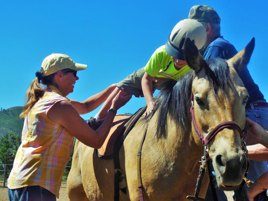 Isaiah climbs into Spirit's saddle at the mounting station.