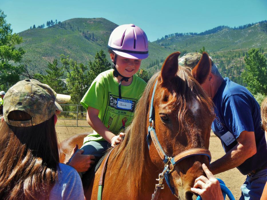 Jacob on Rose as his therapy team checks the stirrups.