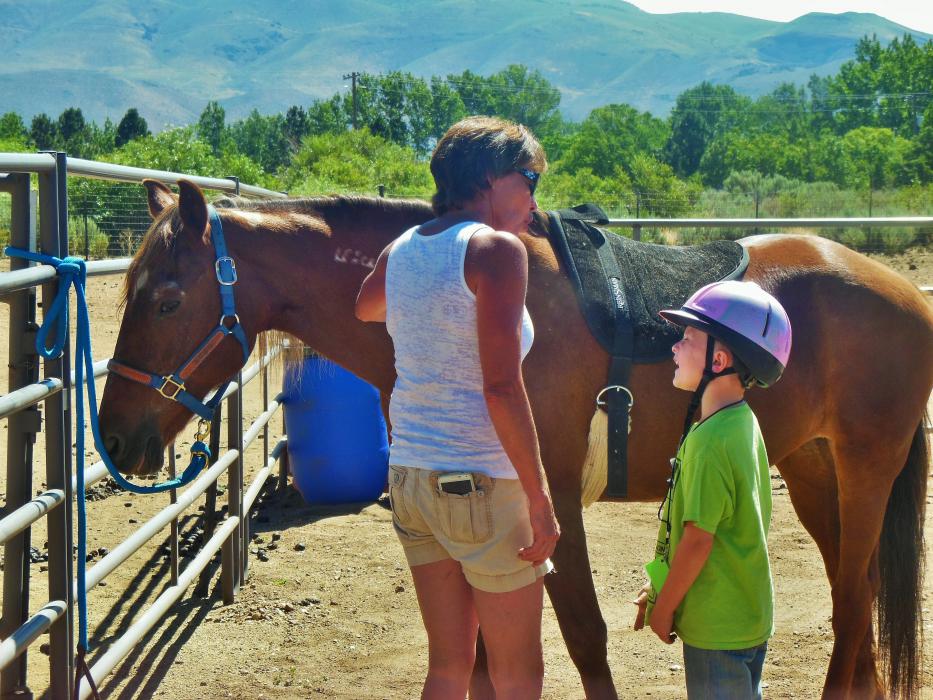 Jacob and his therapist talk as they saddle Rose, a mustang.