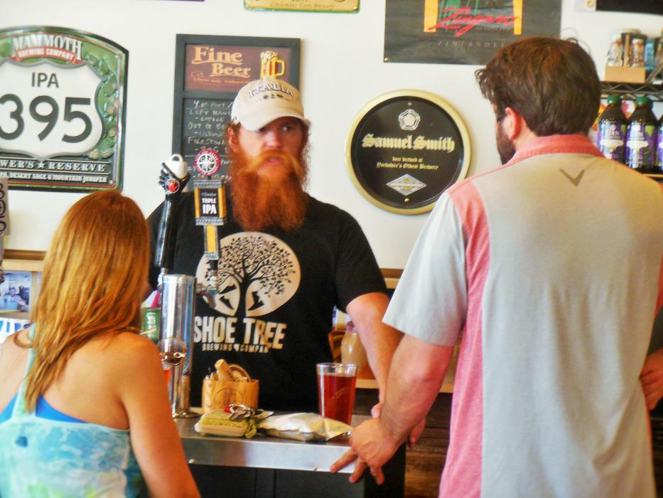 Trevor Rotoli (center) chats with customers at the tap bar inside Just Brew It.