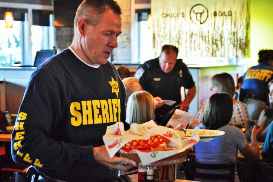 Photo by Brett Fisher. DCSO deputy serves food to customers.