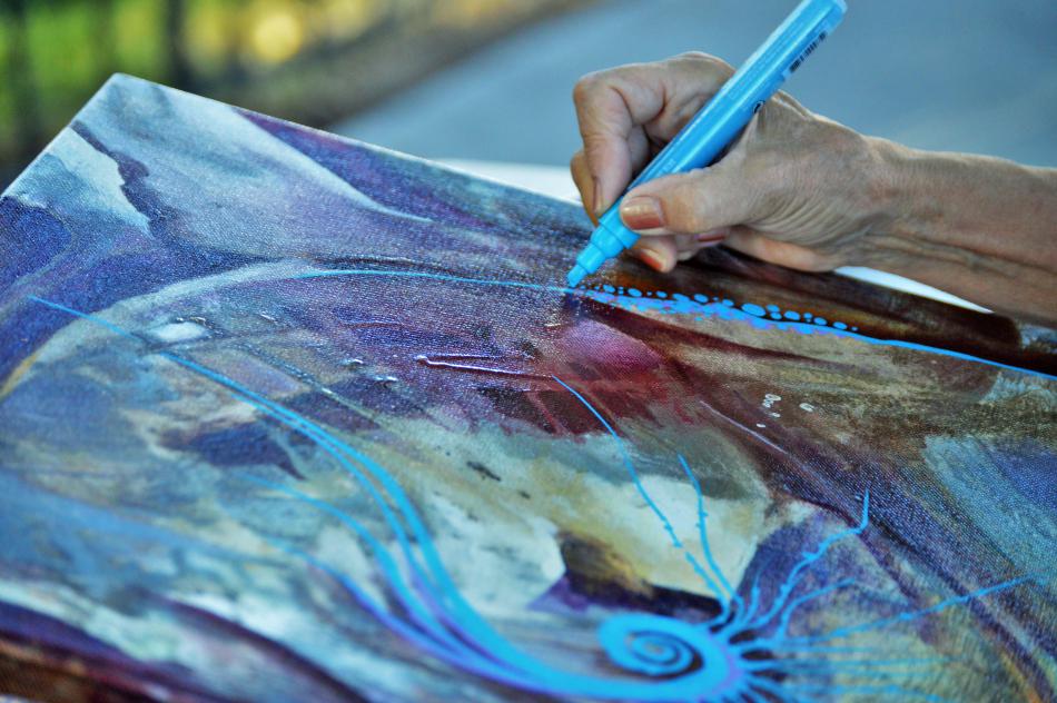 Photo by Brett Fisher. An artist runs a highlighter down her painted canvas.