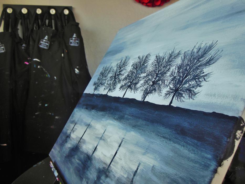 Aprons hang behind a painting at Mona Lisa and Wine.