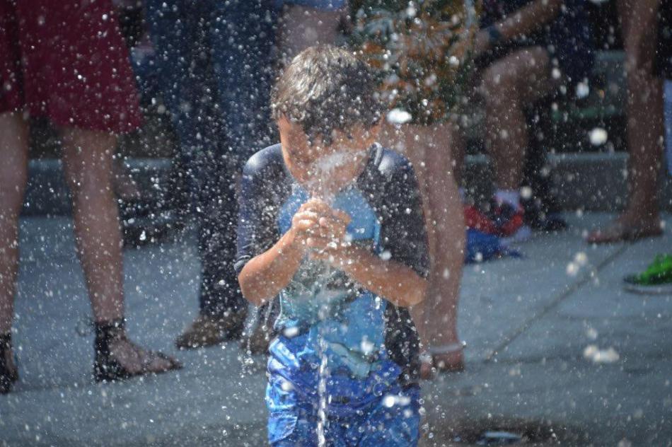 Photo by Lisa Fisher. A boy refreshes himself with sprays of water from the splash pad.