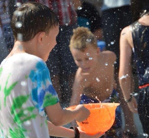 Photo by Lisa Fisher. A boy catches water drops in a hat Saturday morning on the splash pad at Bob McFadden Plaza.
