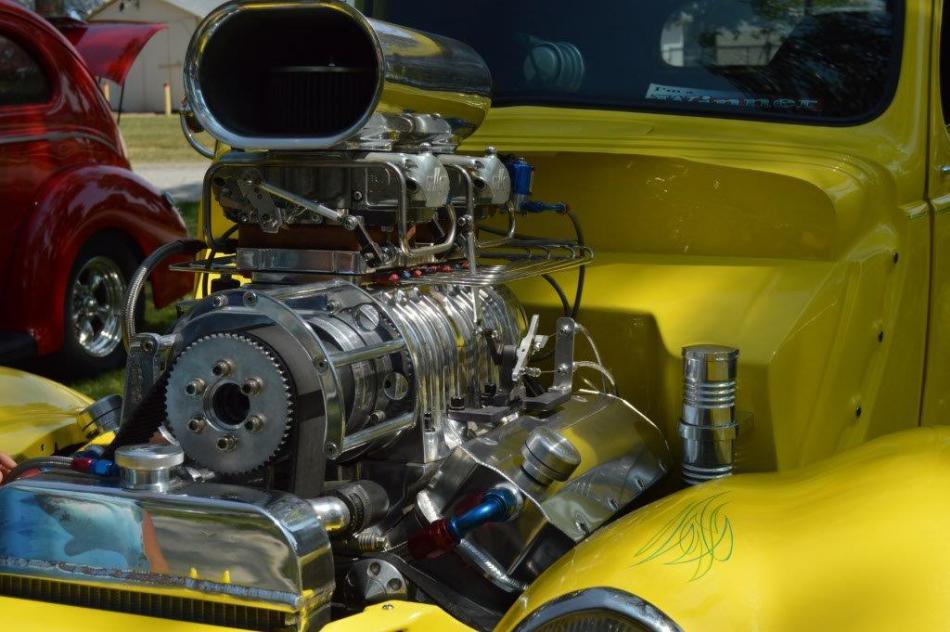 Shining chrome on the raised engine block of a hot rod.