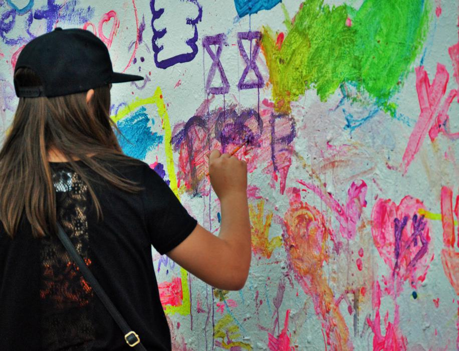 A young woman paints on the art wall Saturday night.