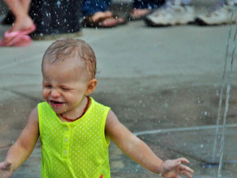 A toddler experiences the splash pad at McFadden plaza.