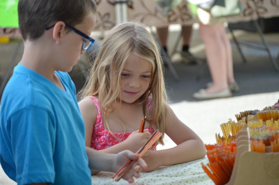 Children delight in honey sticks at the Third and Curry Farmer's Market.
